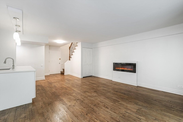 1115 S Plymouth Ct Unit 102, Chicago, IL 60605 - unfurnished living room with dark wood-style flooring, a sink, stairs, a glass covered fireplace, and baseboards