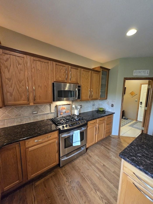 10880 Swallow Tail Ln, Frankfort, IL 60423 - kitchen featuring stainless steel appliances, dark stone counters, light wood-type flooring, backsplash, and brown cabinets