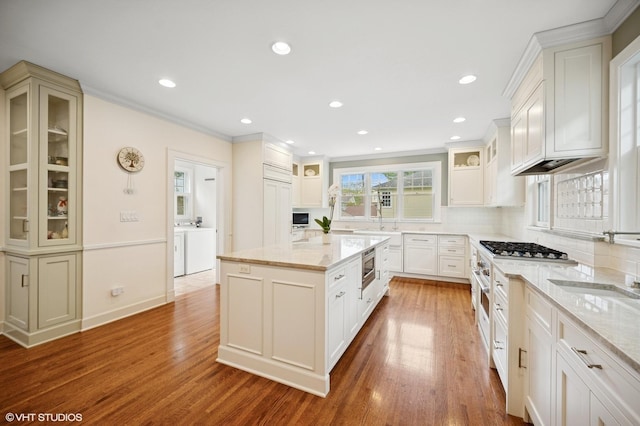 739 Forest Ave, Evanston, IL 60202 - kitchen featuring washing machine and clothes dryer, a sink, decorative backsplash, a kitchen island, and light stone counters