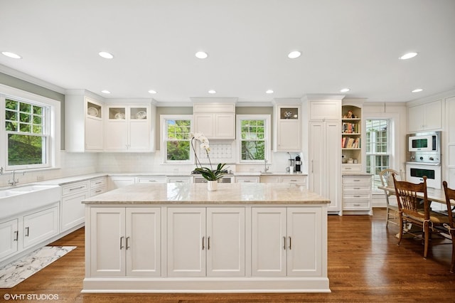 739 Forest Ave, Evanston, IL 60202 - kitchen featuring white oven, stainless steel microwave, a center island, a sink, and white cabinetry