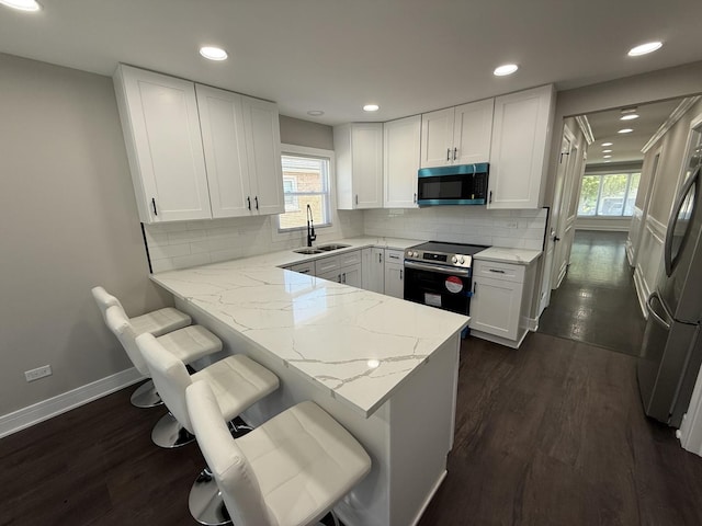 3906 W 117th St, Alsip, IL 60803 - kitchen featuring appliances with stainless steel finishes, light stone counters, white cabinetry, a peninsula, and healthy amount of natural light