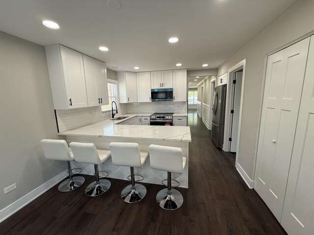 3906 W 117th St, Alsip, IL 60803 - kitchen with stainless steel appliances, a peninsula, backsplash, white cabinetry, and dark wood-style flooring