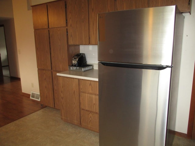 402 Heritage Ln, Ottawa, IL 61350 - kitchen featuring freestanding refrigerator, brown cabinets, tasteful backsplash, and light countertops