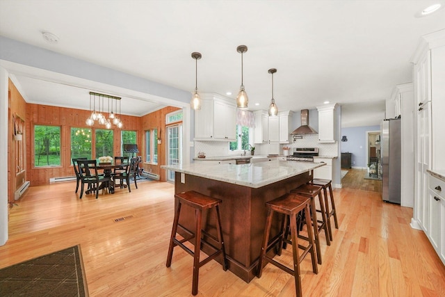 4N307 Knoll Creek Dr, Saint Charles, IL 60175 - kitchen featuring appliances with stainless steel finishes, wall chimney exhaust hood, a baseboard radiator, light wood-style flooring, and white cabinetry