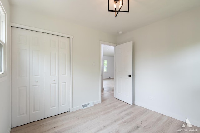 9058 Caddy Ct, Orland Park, IL 60462 - unfurnished bedroom featuring light wood finished floors, a closet, and a chandelier