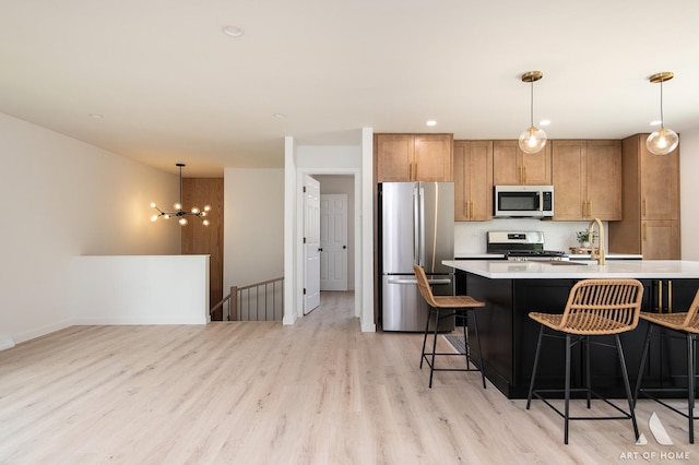 9058 Caddy Ct, Orland Park, IL 60462 - kitchen featuring appliances with stainless steel finishes, light wood-style floors, light countertops, a breakfast bar, and hanging light fixtures