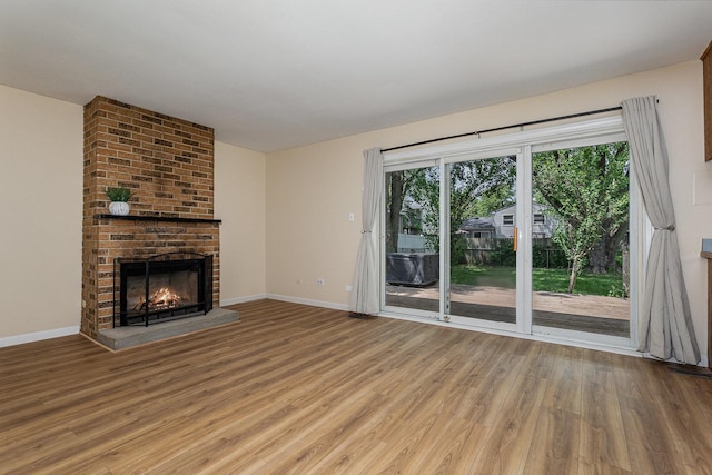 931 Mosby Ct, Joliet, IL 60431 - unfurnished living room featuring light wood-type flooring, a brick fireplace, and baseboards