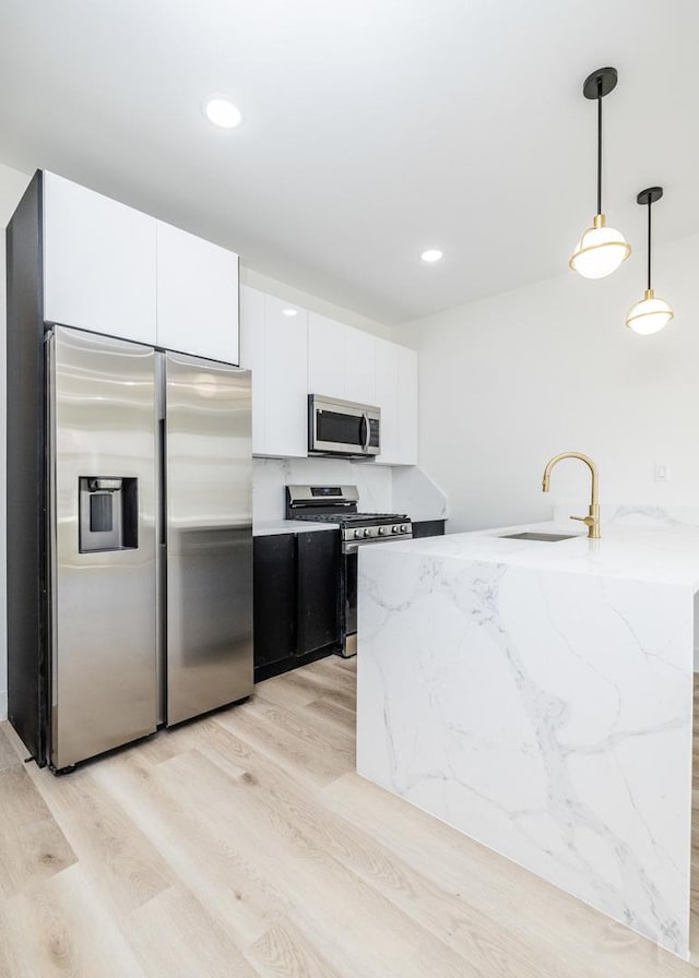 5534 S Michigan Ave, Chicago, IL 60637 - kitchen featuring stainless steel appliances, a sink, light wood-style flooring, white cabinetry, and decorative light fixtures