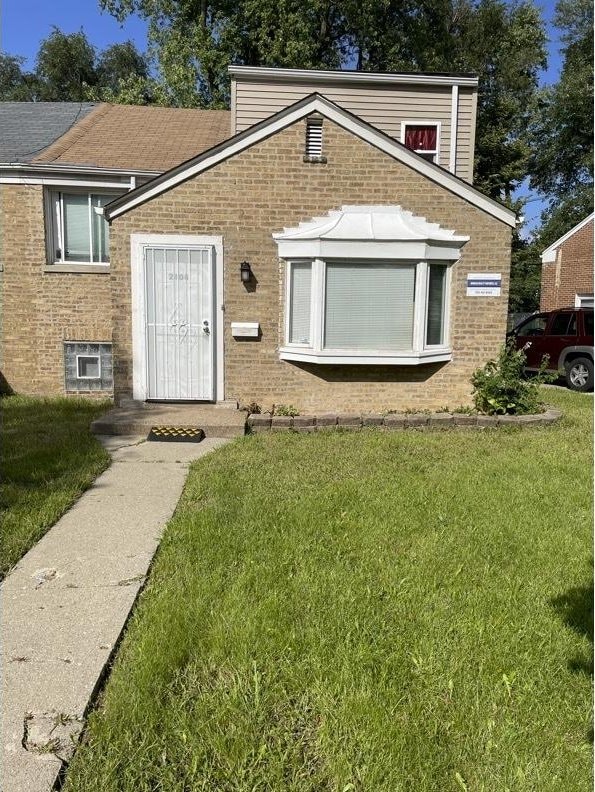 2404 E 97th St, Chicago, IL 60617 - view of front facade featuring brick siding and a front lawn