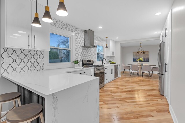 274 University Dr, Buffalo Grove, IL 60089 - kitchen with stainless steel appliances, wall chimney range hood, a peninsula, decorative backsplash, and light wood-type flooring