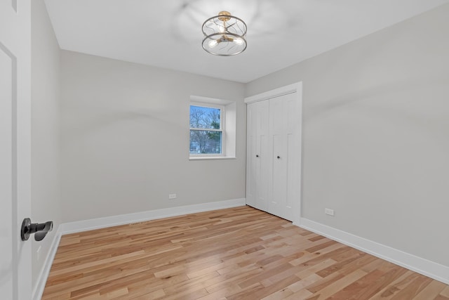 274 University Dr, Buffalo Grove, IL 60089 - unfurnished bedroom featuring light wood-type flooring, a chandelier, baseboards, and a closet