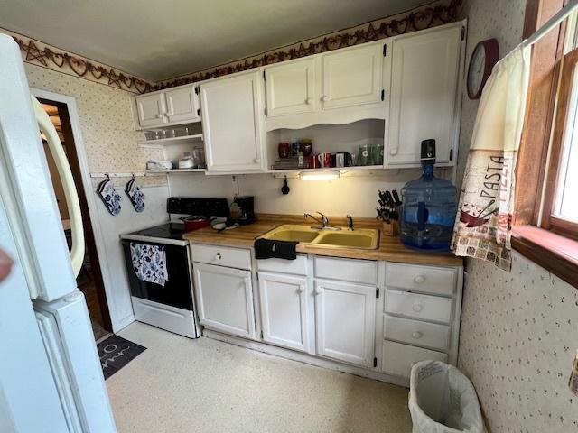 520 W American St, Freeport, IL 61032 - kitchen featuring electric range oven, a sink, open shelves, wallpapered walls, and freestanding refrigerator