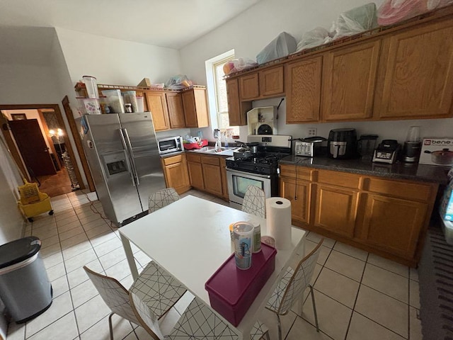 1530 N Springfield Ave, Chicago, IL 60651 - kitchen with appliances with stainless steel finishes, brown cabinetry, light tile patterned floors, dark countertops, and a sink