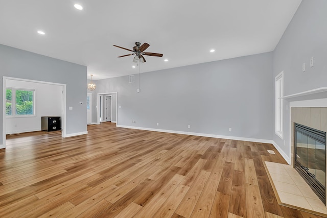 405 S Carol Ln, Braidwood, IL 60408 - unfurnished living room with light wood finished floors, ceiling fan, a tile fireplace, a chandelier, and baseboards