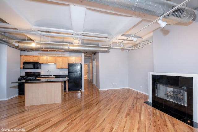 500 S Clinton St Unit 604, Chicago, IL 60607 - kitchen featuring black appliances, light brown cabinets, light wood-style flooring, baseboards, and a kitchen island