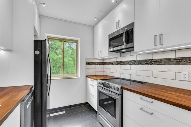 1910 Melrose Dr Unit C, Champaign, IL 61820 - kitchen featuring wooden counters, stainless steel appliances, decorative backsplash, dark tile patterned flooring, and white cabinets