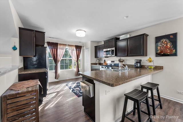 2346 Aurora Dr, Pingree Grove, IL 60140 - kitchen featuring appliances with stainless steel finishes, a sink, dark wood-type flooring, a kitchen bar, and a peninsula