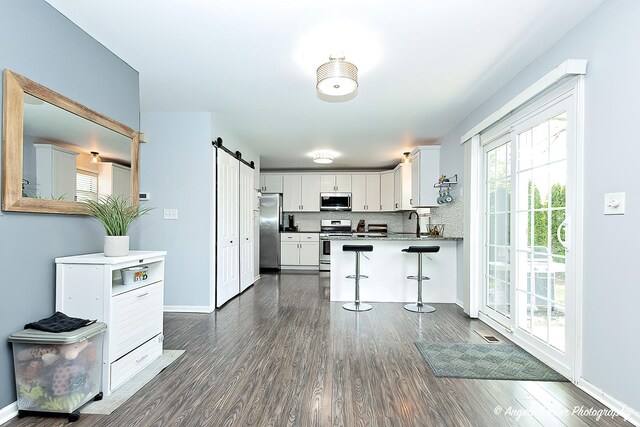 1381 Regency Ln, Lake Villa, IL 60046 - kitchen with stainless steel appliances, a barn door, a breakfast bar, white cabinets, and a sink