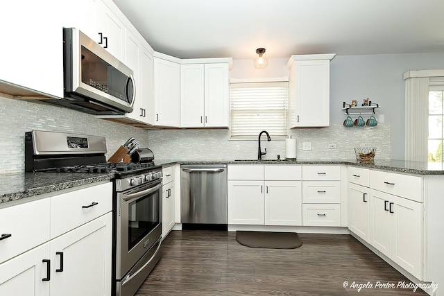 1381 Regency Ln, Lake Villa, IL 60046 - kitchen featuring appliances with stainless steel finishes, a sink, white cabinetry, dark stone counters, and a peninsula