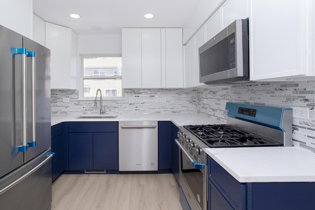 34382 N Aster Ct, Round Lake Beach, IL 60073 - kitchen with appliances with stainless steel finishes, a sink, blue cabinets, light wood finished floors, and backsplash