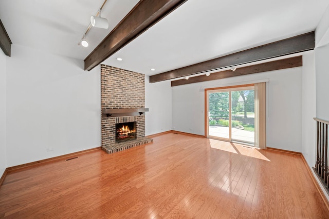 720 Dunhill Dr, Buffalo Grove, IL 60089 - unfurnished living room featuring track lighting, beam ceiling, wood finished floors, and a brick fireplace