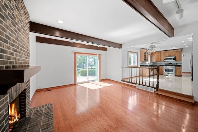 720 Dunhill Dr, Buffalo Grove, IL 60089 - unfurnished living room with beam ceiling, light wood finished floors, a brick fireplace, a ceiling fan, and rail lighting