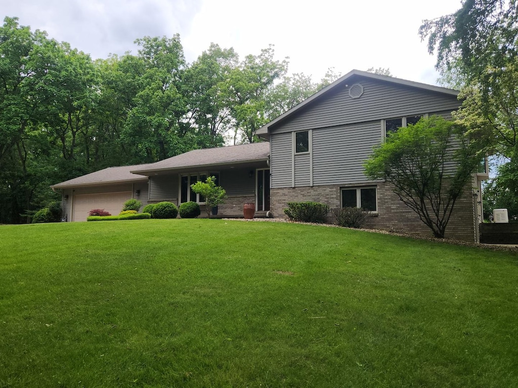 847 Lake Wildwood Dr, Varna, IL 61375 - tri-level home featuring an attached garage, a front lawn, and brick siding