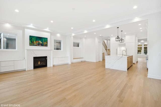4242 N Winchester Ave, Chicago, IL 60613 - unfurnished living room featuring a sink, light wood-style flooring, recessed lighting, stairway, and a fireplace