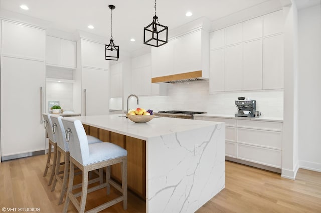 4242 N Winchester Ave, Chicago, IL 60613 - kitchen with backsplash, light wood-style floors, recessed lighting, a center island with sink, and a breakfast bar