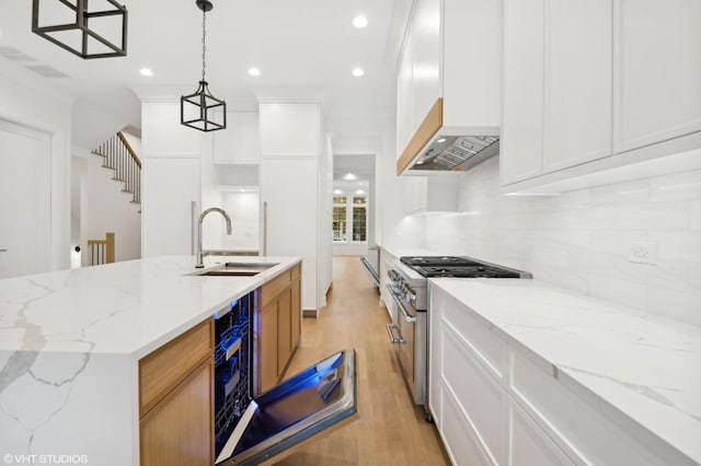 4242 N Winchester Ave, Chicago, IL 60613 - kitchen with a sink, wall chimney exhaust hood, high end stove, light wood-style flooring, and backsplash