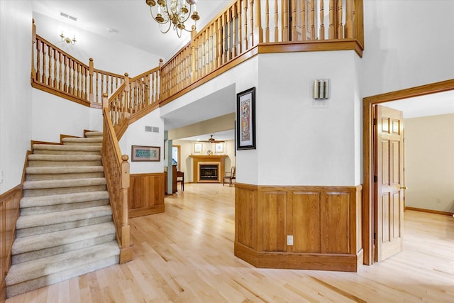 1206 Wilshire Ct, Champaign, IL 61821 - staircase featuring wood finished floors, a fireplace, a high ceiling, a chandelier, and a wainscoted wall