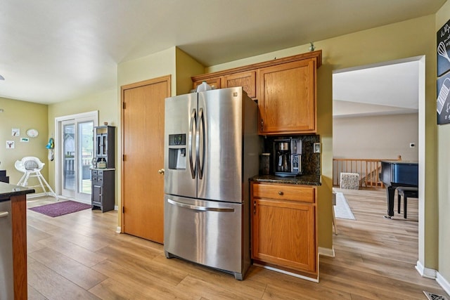 1043 San Mateo Dr, Romeoville, IL 60446 - kitchen featuring stainless steel fridge with ice dispenser, light wood-style flooring, brown cabinetry, baseboards, and dark stone counters