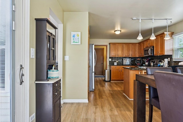 1043 San Mateo Dr, Romeoville, IL 60446 - kitchen with appliances with stainless steel finishes, track lighting, brown cabinetry, backsplash, and light wood-style flooring