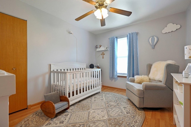 1043 San Mateo Dr, Romeoville, IL 60446 - bedroom with light wood-type flooring, a crib, ceiling fan, and baseboards