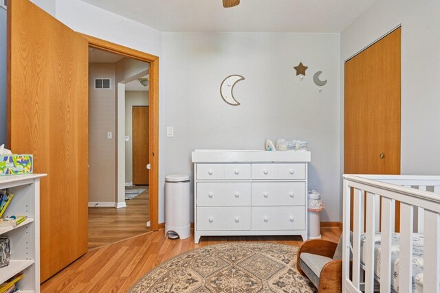 1043 San Mateo Dr, Romeoville, IL 60446 - bedroom featuring light wood-style floors, a crib, and baseboards