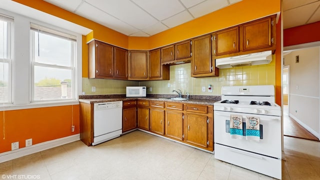 4608 W Altgeld St, Chicago, IL 60639 - kitchen with white appliances, under cabinet range hood, brown cabinets, decorative backsplash, and a drop ceiling