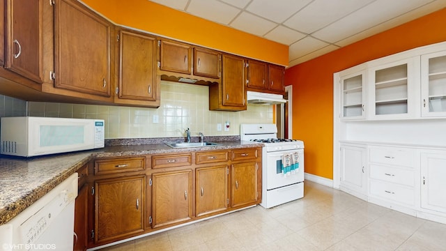 4608 W Altgeld St, Chicago, IL 60639 - kitchen with white appliances, a sink, under cabinet range hood, brown cabinets, and decorative backsplash