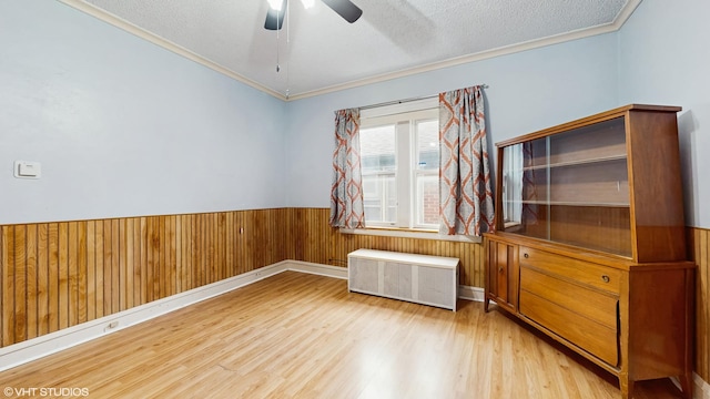 4608 W Altgeld St, Chicago, IL 60639 - empty room featuring radiator heating unit, wood finished floors, ornamental molding, ceiling fan, and wainscoting