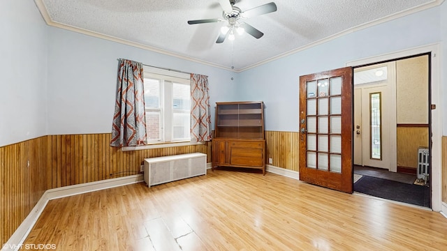 4608 W Altgeld St, Chicago, IL 60639 - spare room featuring radiator heating unit, a textured ceiling, wooden walls, wood finished floors, and wainscoting