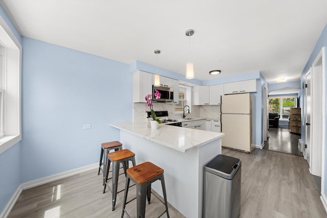 1723 W 75th Pl, Chicago, IL 60620 - kitchen featuring white appliances, light wood-style flooring, a peninsula, and light stone countertops