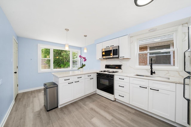 1723 W 75th Pl, Chicago, IL 60620 - kitchen featuring range with gas cooktop, stainless steel microwave, a sink, a peninsula, and light wood-style floors