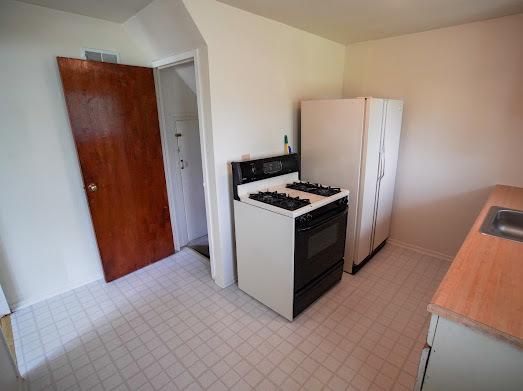 64 Ash St, Park Forest, IL 60466 - kitchen featuring gas stove, freestanding refrigerator, light countertops, a sink, and light floors