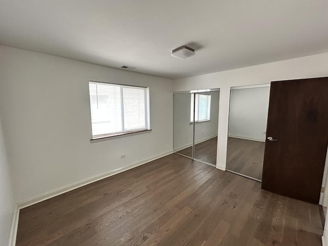 9814 Bianco Ter Unit 1B, Des Plaines, IL 60016 - unfurnished bedroom featuring two closets, dark wood-style flooring, and baseboards