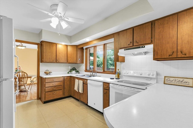 1207 W Kirby Ave, Champaign, IL 61821 - kitchen featuring white appliances, under cabinet range hood, light floors, brown cabinetry, and light countertops