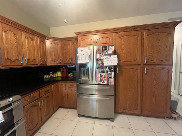 1131 S Nelson Ave, Kankakee, IL 60901 - kitchen featuring appliances with stainless steel finishes, light tile patterned floors, brown cabinetry, and dark countertops