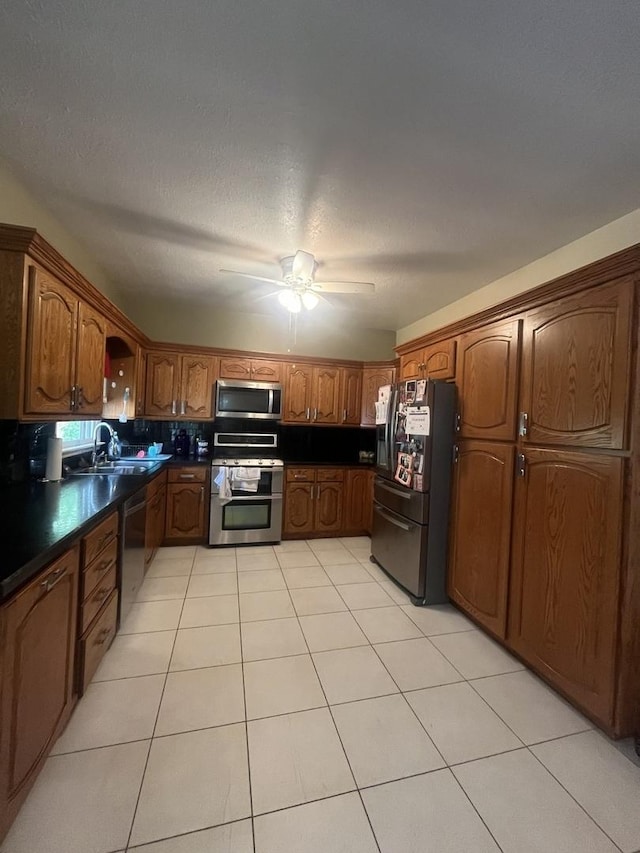 1131 S Nelson Ave, Kankakee, IL 60901 - kitchen with appliances with stainless steel finishes, dark countertops, a sink, ceiling fan, and brown cabinets