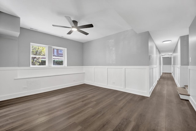 849 W Belle Plaine Ave Unit G, Chicago, IL 60613 - empty room with a ceiling fan, a wainscoted wall, dark wood-style floors, and a decorative wall