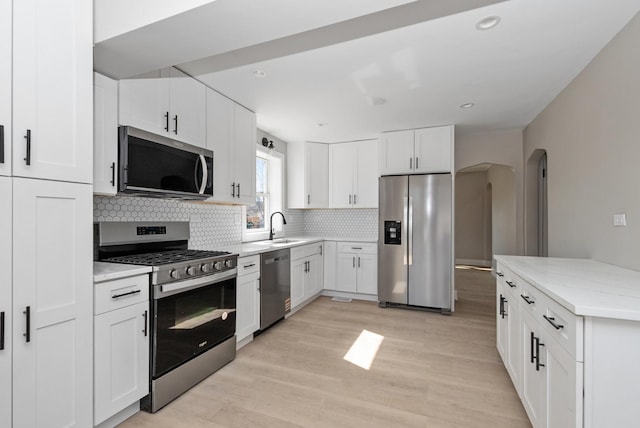 9841 Cook Ave, Oak Lawn, IL 60453 - kitchen featuring stainless steel appliances, a sink, arched walkways, decorative backsplash, and light stone counters