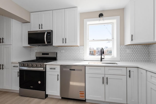9841 Cook Ave, Oak Lawn, IL 60453 - kitchen with appliances with stainless steel finishes, a sink, white cabinetry, light wood-style floors, and decorative backsplash
