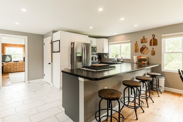 707 Coolidge Pl, Rockford, IL 61107 - kitchen with appliances with stainless steel finishes, white cabinetry, a sink, a peninsula, and a breakfast bar area